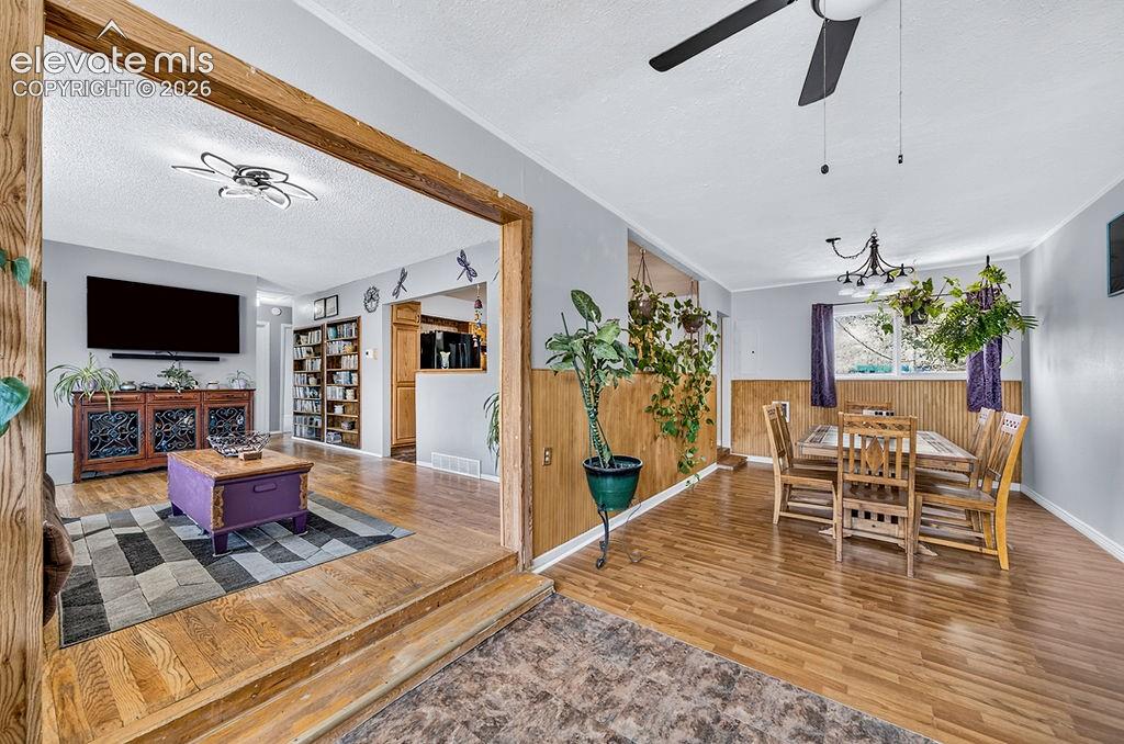 Image 21 of 44: Dining area featuring wood-finish flooring, wood paneling, and a multi-ligh