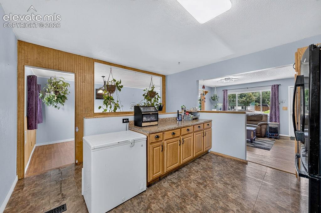 Image 26 of 44: Kitchen with wood-finish flooring, light wood cabinetry, and a speckled cou