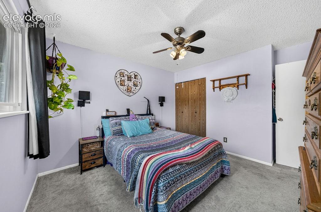 Image 27 of 44: Bedroom featuring textured ceiling, light-toned carpeting, and a ceiling fa