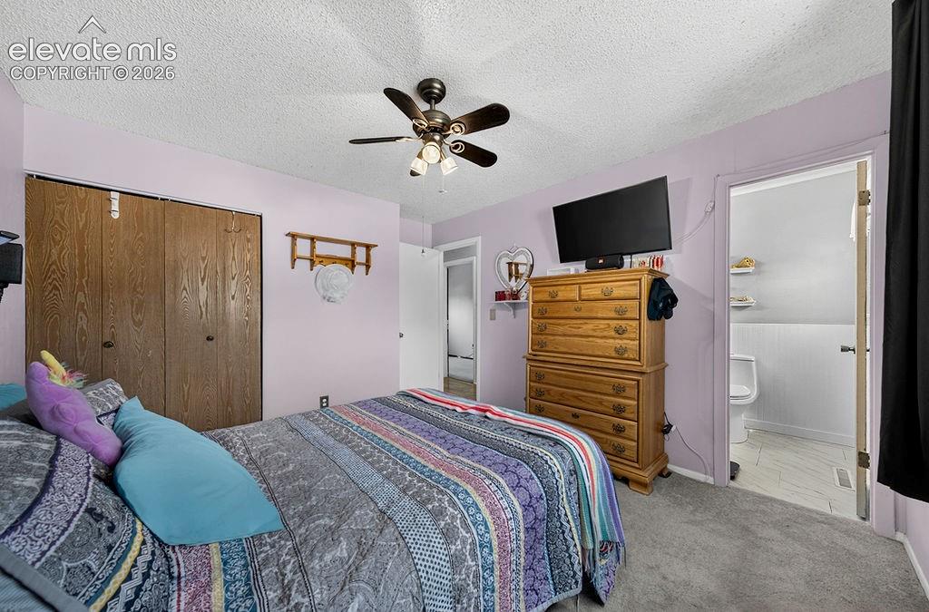 Image 28 of 44: Carpeted bedroom featuring a ceiling fan with light fixture, wood-finish bi
