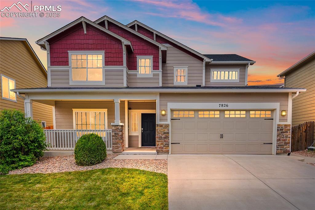 Caption: Craftsman-style house featuring driveway, stone siding, covered porch, an attached garage, and a fro