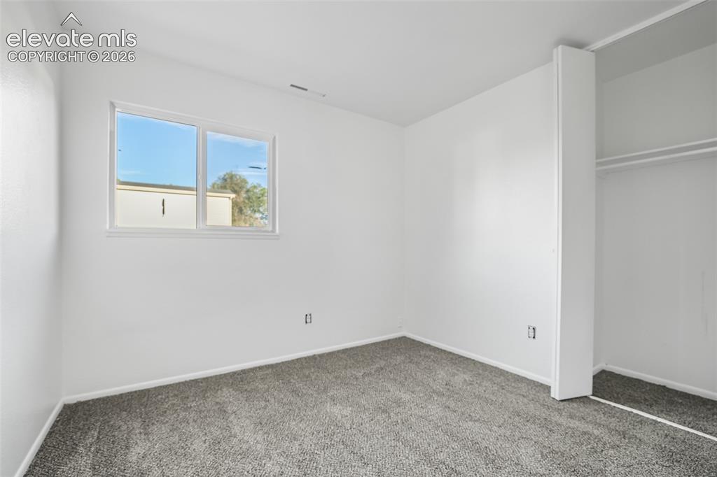 Image 11 of 19: Bright secondary bedroom featuring neutral carpet flooring, a large window 