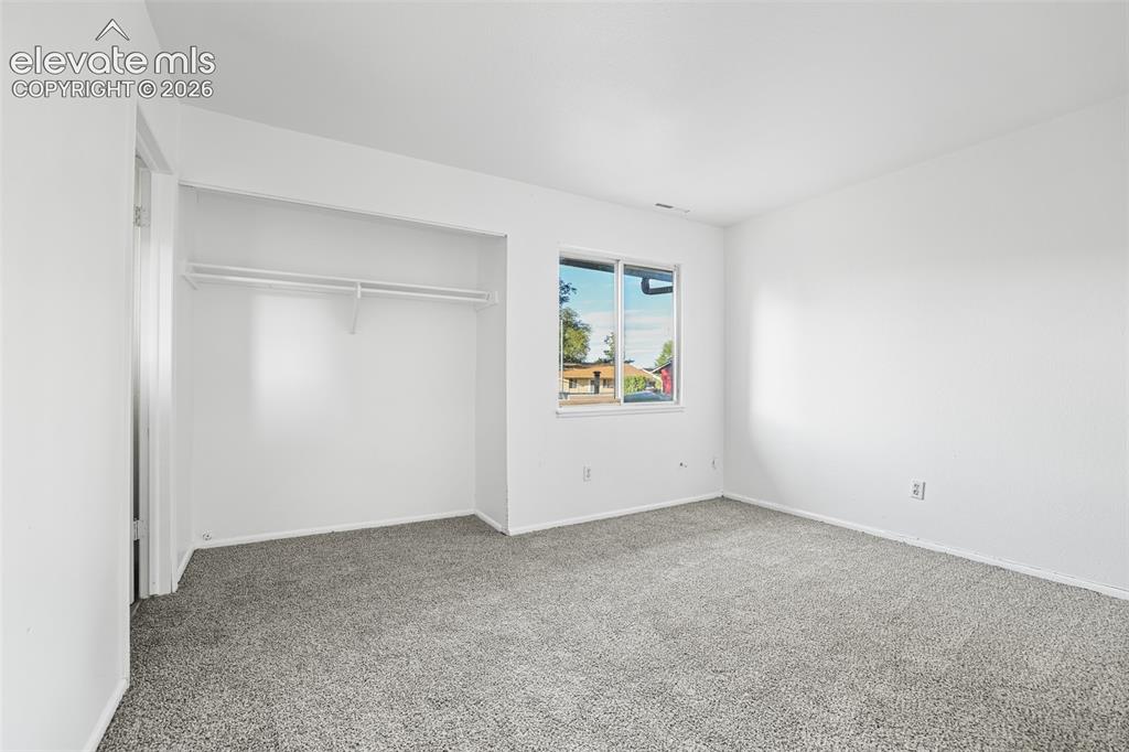 Image 13 of 19: Spacious bedroom featuring neutral carpeting, a large closet with sliding d