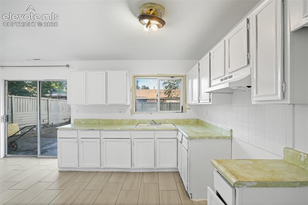 Image 5 of 19: Bright, open kitchen featuring white cabinetry, dual countertop surfaces wi