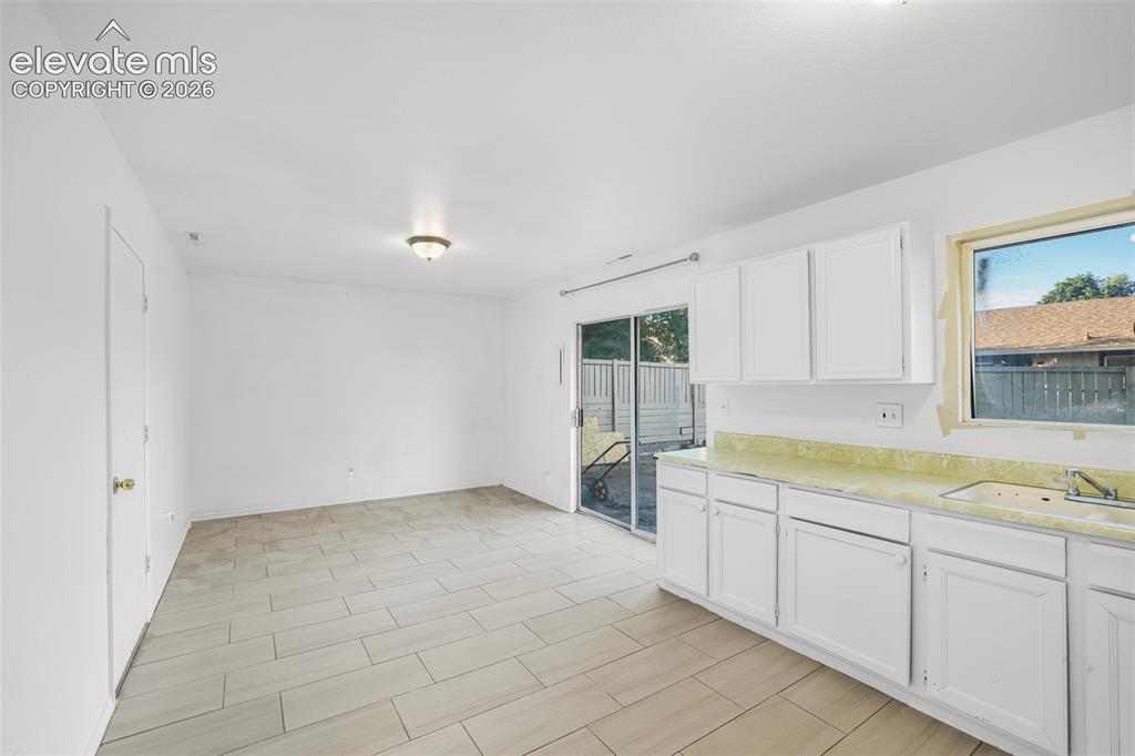 Image 6 of 19: Open concept living space featuring white cabinetry, light-toned tile floor