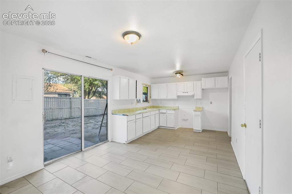 Image 8 of 19: Kitchen area with white cabinetry, light-toned countertops, and light tile