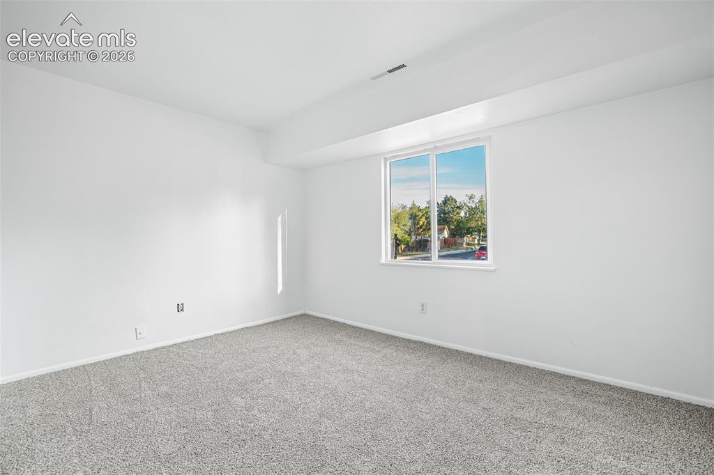 Image 9 of 19: Bright room featuring a large window, neutral gray carpeting, white walls, 