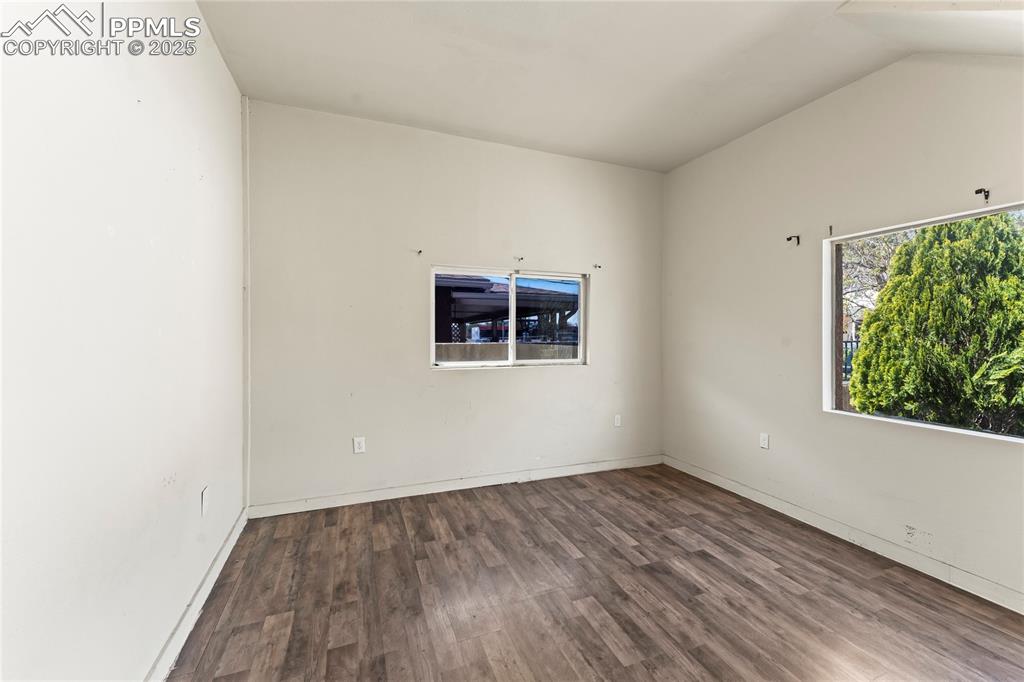 Image 10 of 36: Spare room featuring baseboards, vaulted ceiling, and wood finished floors