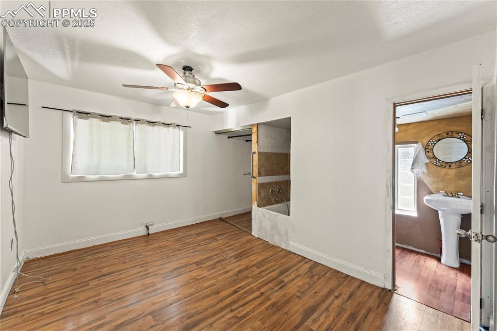 Image 12 of 36: Spare room featuring baseboards, ceiling fan, a sink, and wood finished flo