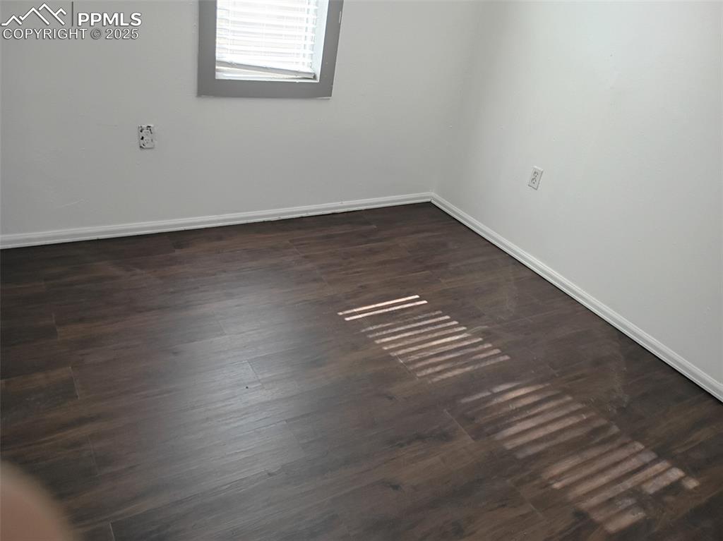 Image 14 of 36: Empty room featuring baseboards and dark wood-style floors