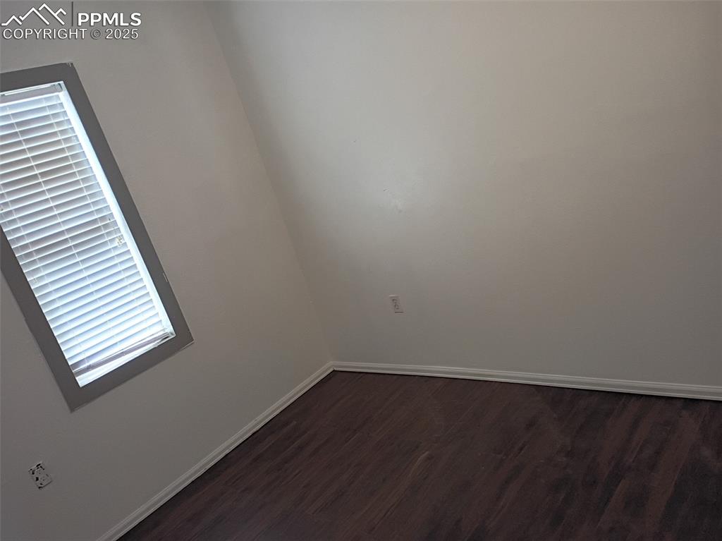 Image 15 of 36: Unfurnished room with dark wood-type flooring and baseboards