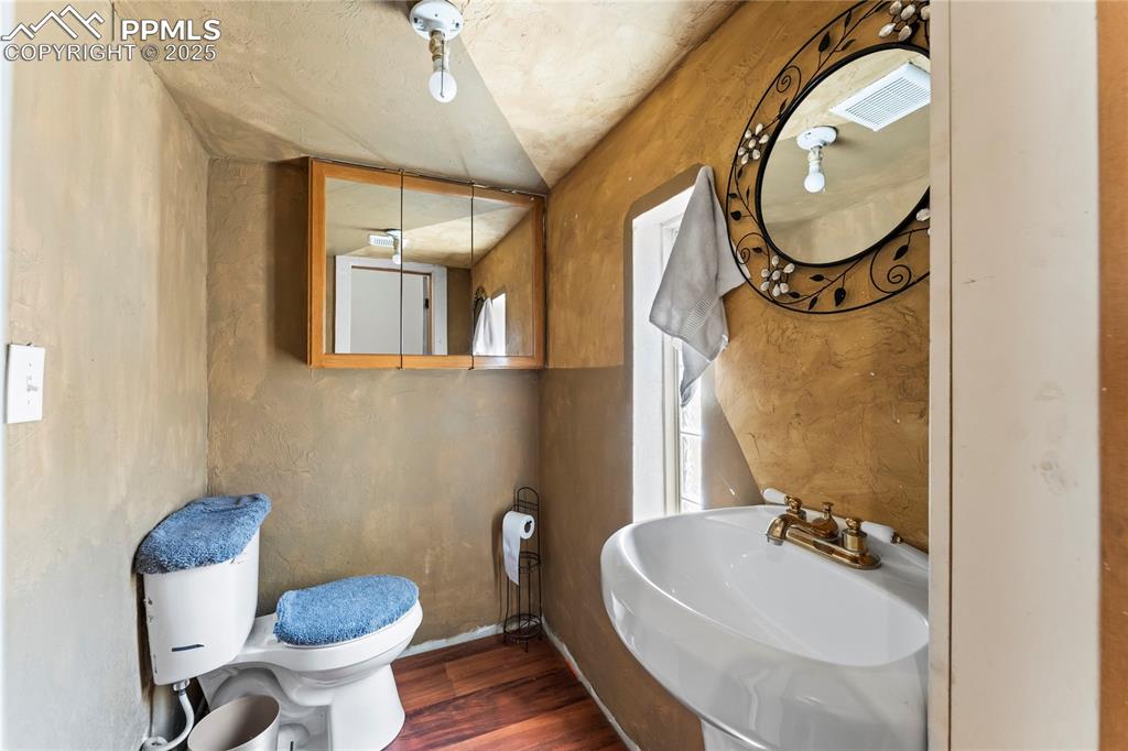 Image 16 of 36: Half bathroom featuring visible vents, wood finished floors, toilet, basebo