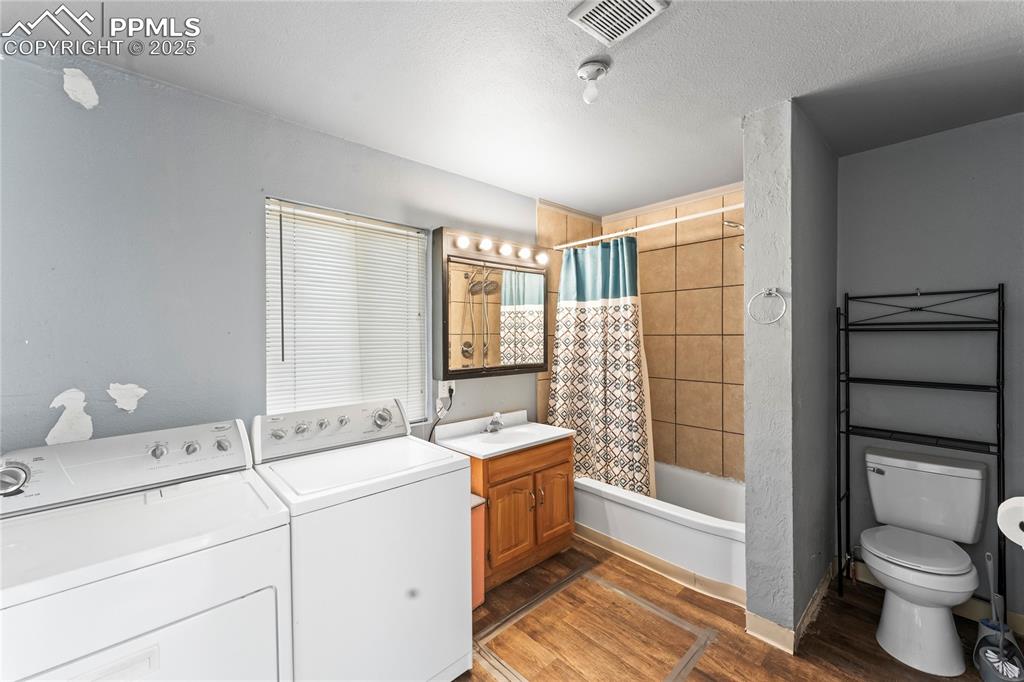 Image 17 of 36: Full bathroom with toilet, wood finished floors, shower / tub combo, visibl