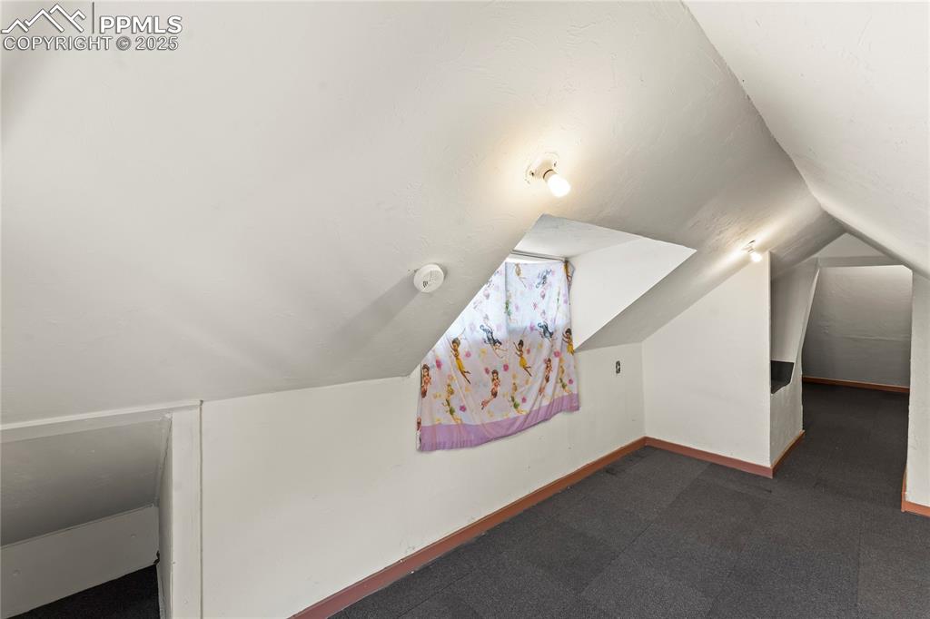 Image 19 of 36: Additional living space with baseboards, vaulted ceiling, and dark colored 