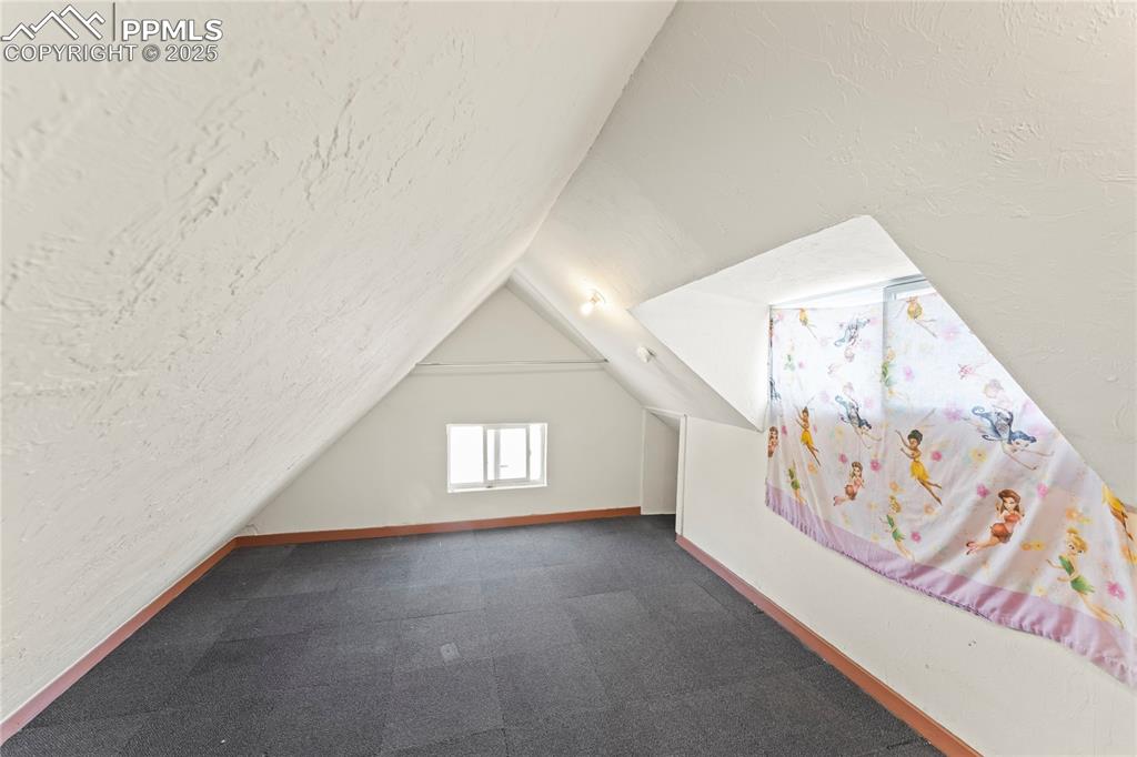 Image 20 of 36: Bonus room with baseboards and vaulted ceiling