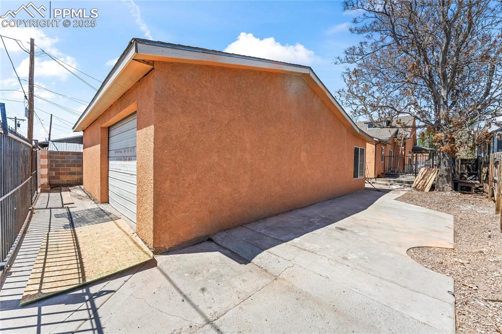 Image 24 of 36: View of side of home with fence, a patio area, and stucco siding
