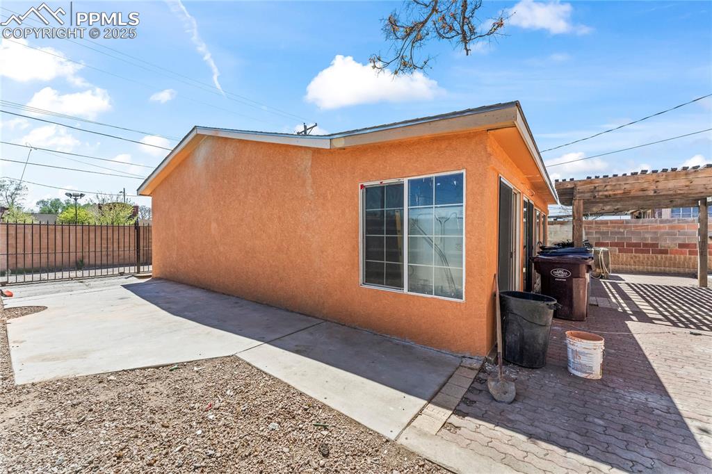 Image 25 of 36: View of property exterior with fence, stucco siding, and a patio area