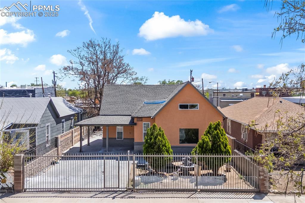 Image 35 of 36: Rustic home featuring stucco siding, a shingled roof, a gate, a fenced fron