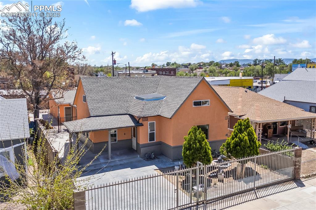 Image 36 of 36: Rustic home with a shingled roof, a fenced front yard, stucco siding, and a