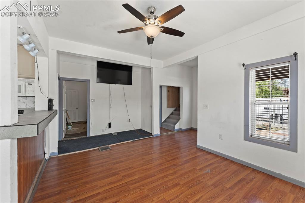 Image 6 of 36: Unfurnished living room with a ceiling fan, visible vents, baseboards, dark