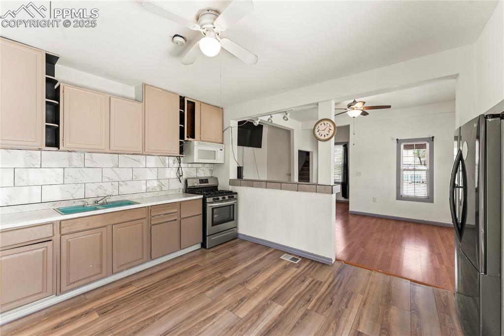 Image 8 of 36: Kitchen featuring open shelves, ceiling fan, a sink, light wood finished fl