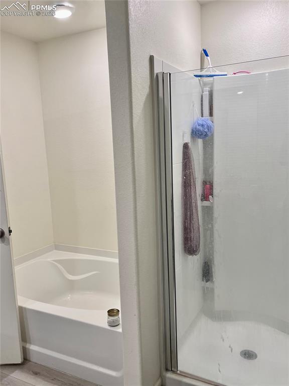 Image 12 of 17: Bathroom featuring a bath, a shower stall, and light wood-style flooring