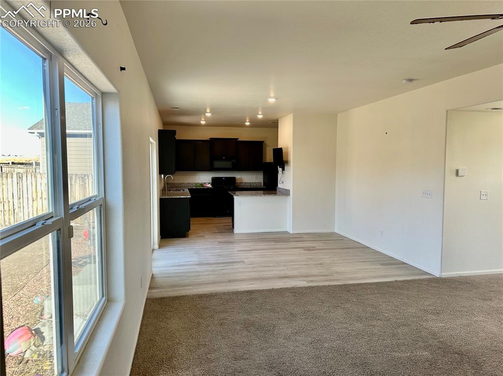 Image 6 of 17: Kitchen featuring open floor plan, light colored carpet, a ceiling fan, bla