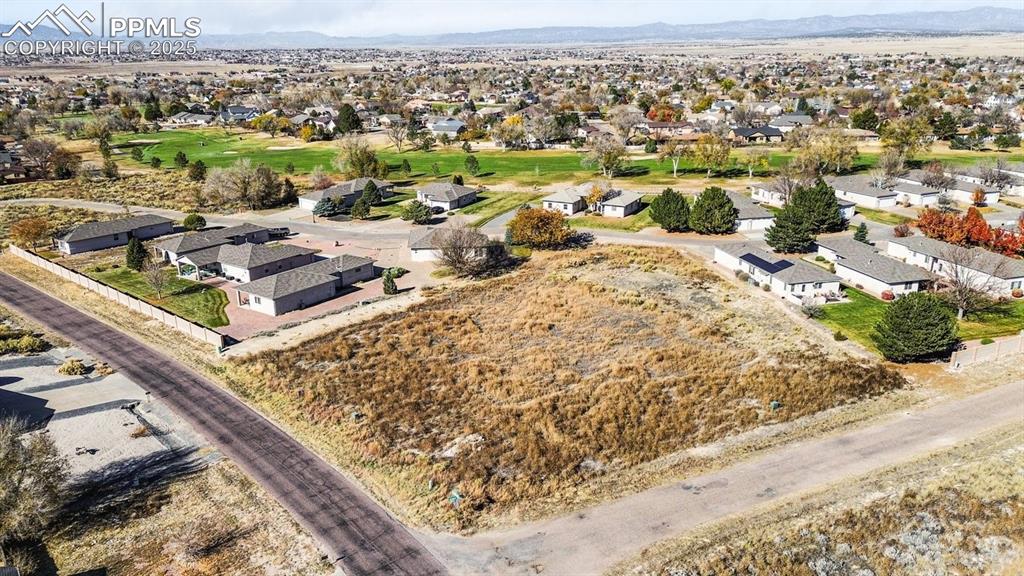 Caption: Aerial view of residential area featuring mountains and a golf club