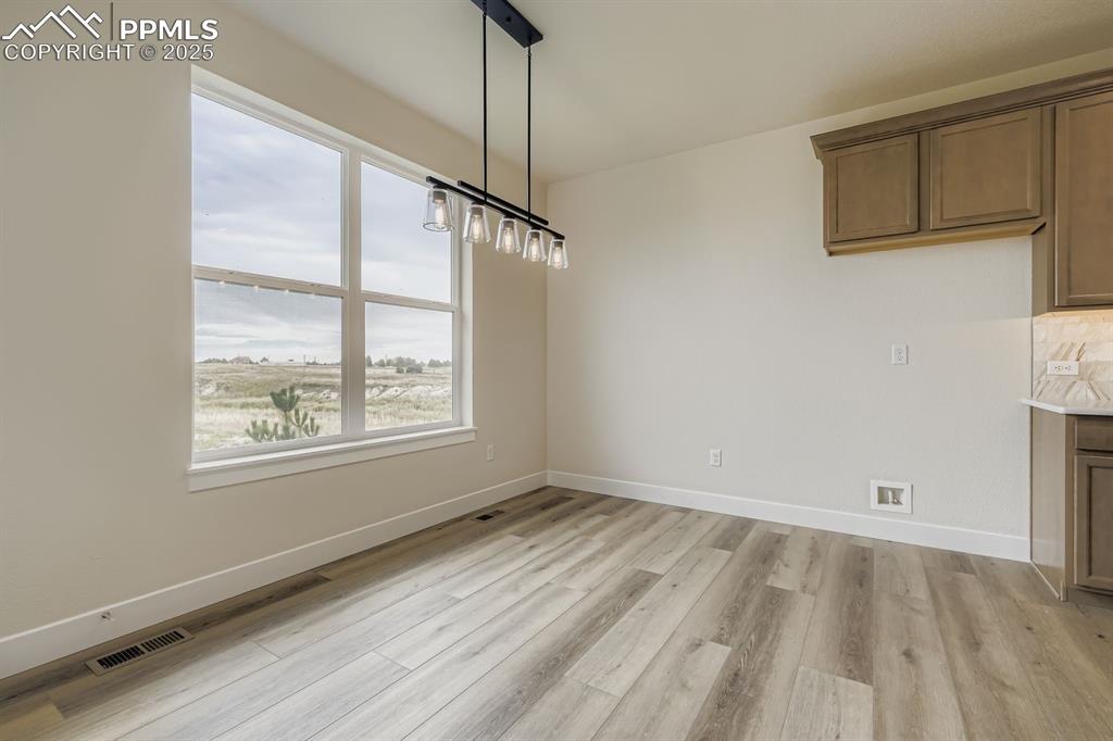 Image 11 of 28: Unfurnished dining area with baseboards and light wood finished floors