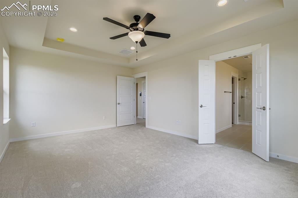 Image 14 of 28: Unfurnished bedroom with a raised ceiling, light carpet, recessed lighting,