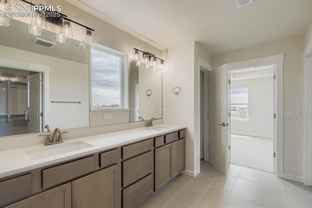 Image 16 of 28: Bathroom with double vanity, light tile patterned floors, and a closet