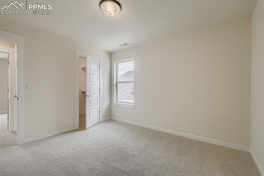 Image 18 of 28: Unfurnished bedroom featuring a spacious closet and light colored carpet