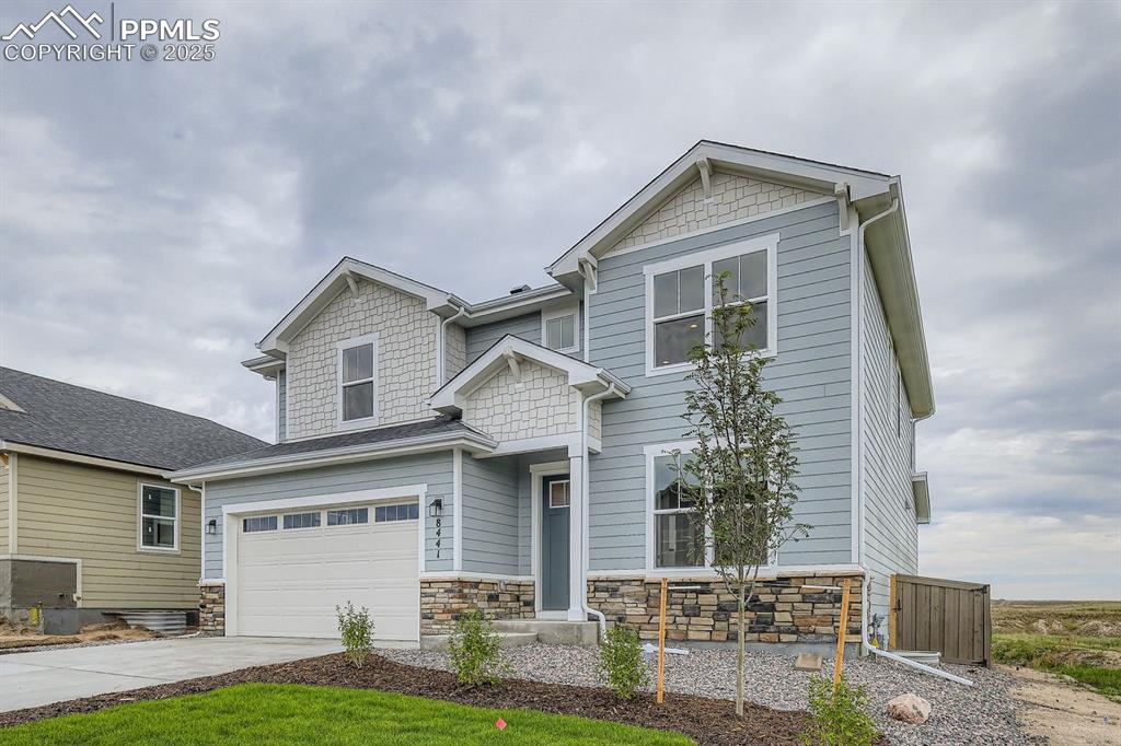 Image 2 of 28: Craftsman-style house with driveway, an attached garage, and stone siding