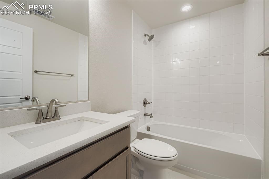 Image 25 of 28: Bathroom featuring shower / bathtub combination, vanity, and a textured wal