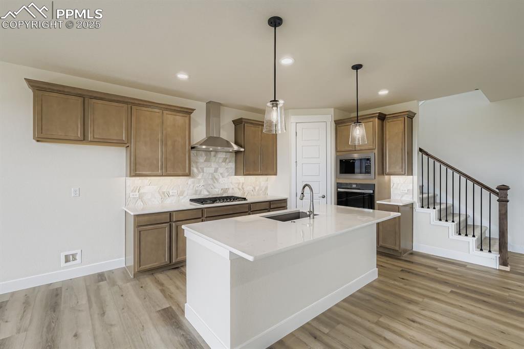 Image 8 of 28: Kitchen featuring decorative backsplash, brown cabinetry, hanging light fix