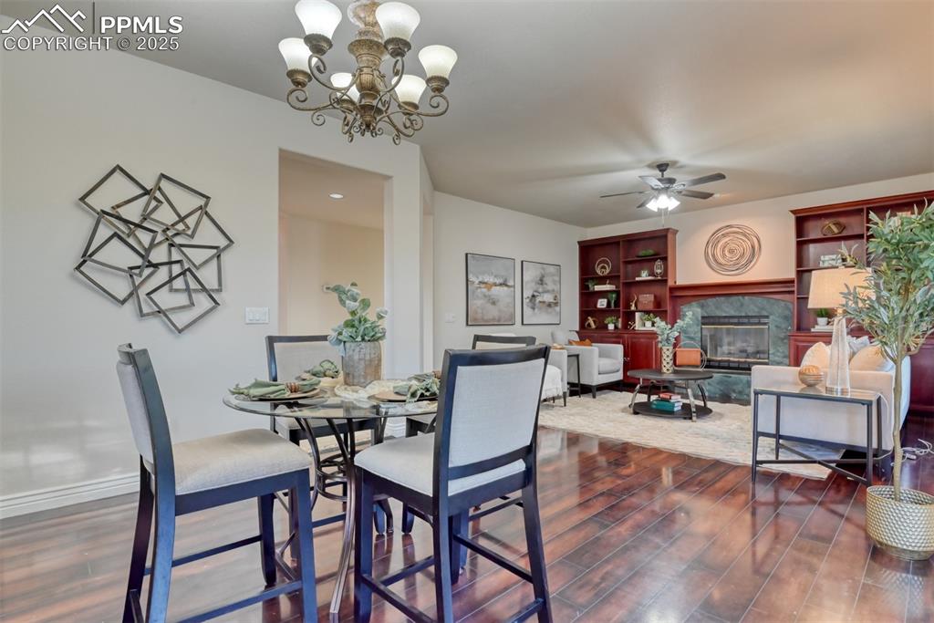 Image 10 of 44: Dining room featuring a fireplace, dark wood-style floors, a chandelier, an
