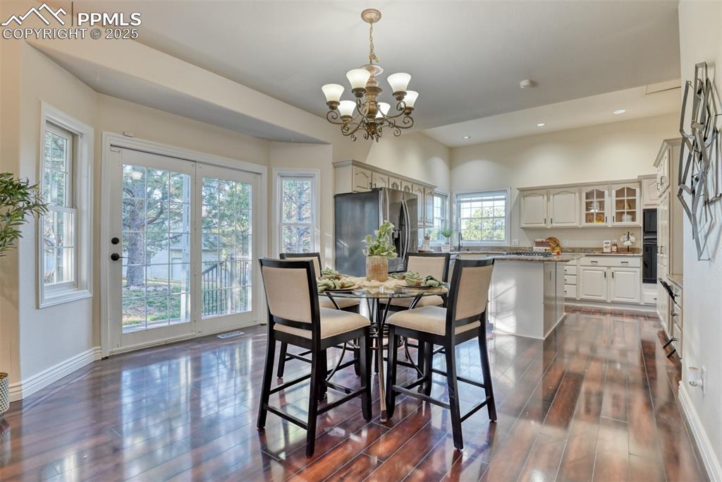 Image 14 of 44: Dining area with dark wood finished floors, recessed lighting, and a chande