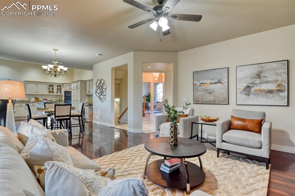 Image 18 of 44: Living room with dark wood-style floors, a chandelier, and a ceiling fan