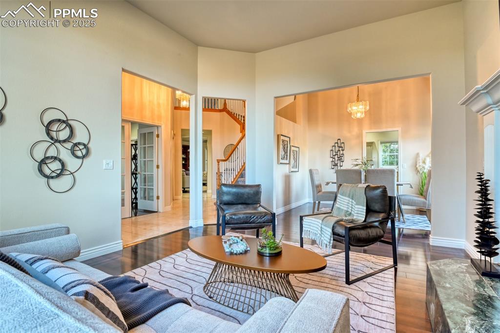 Image 20 of 44: Living room featuring wood finished floors, a towering ceiling, a chandelie