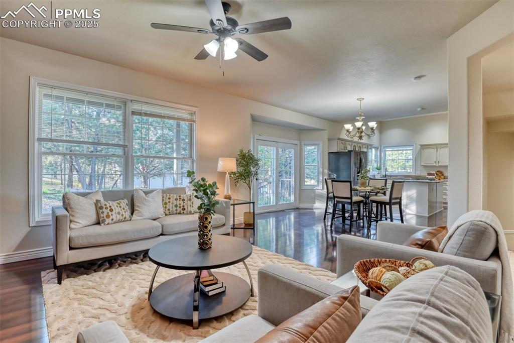 Image 22 of 44: Living area featuring wood finished floors, a chandelier, and a ceiling fan