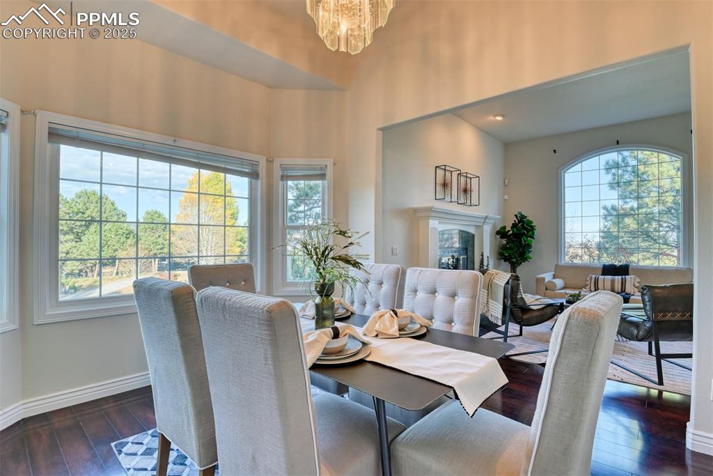 Image 23 of 44: Dining space featuring dark wood-style flooring, a chandelier, and a glass 