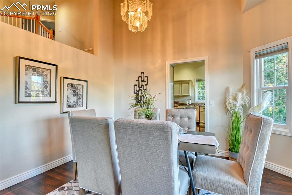 Image 24 of 44: Dining space with dark wood-style floors, a chandelier, and a towering ceil