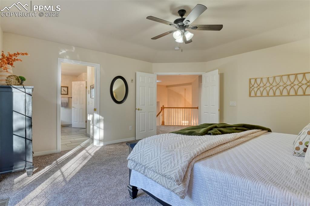 Image 29 of 44: Carpeted bedroom with ensuite bathroom and a ceiling fan