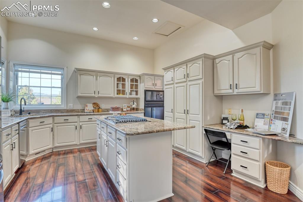 Image 3 of 44: Kitchen with light stone countertops, recessed lighting, glass insert cabin