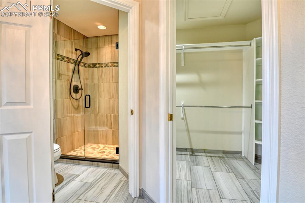 Image 34 of 44: Bathroom with a walk in closet, a stall shower, and recessed lighting