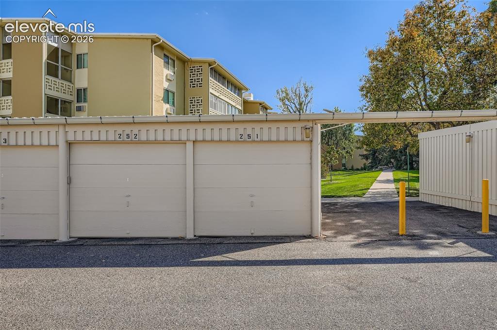 Image 11 of 27: Individual garage spaces with roll-up doors and a paved asphalt drive