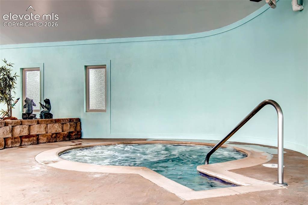 Image 18 of 27: Built-in spa with polished handrail, surrounded by textured concrete deckin