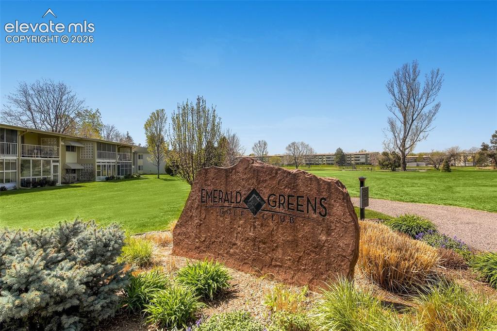 Image 22 of 27: Property entrance featuring a stone monument sign, landscaped beds, a paved