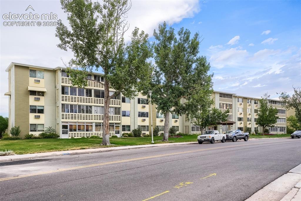 Image 26 of 27: Multi-story building featuring light-colored exterior walls and multiple ba
