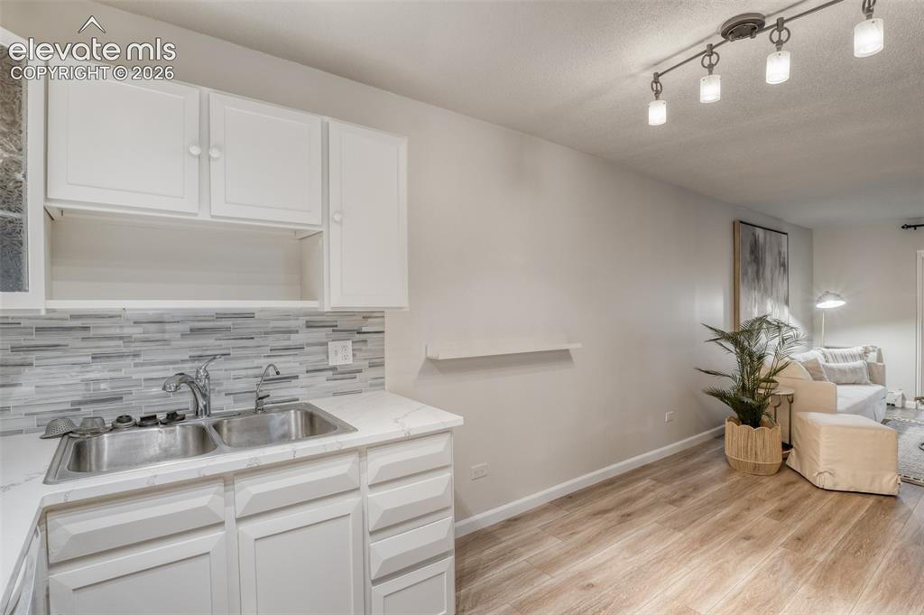 Image 5 of 27: Kitchenette with white cabinetry, a double basin stainless steel sink, and